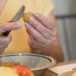 A woman cutting an apple with a knife.