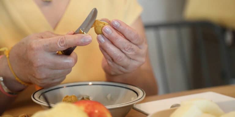 A woman cutting an apple with a knife.