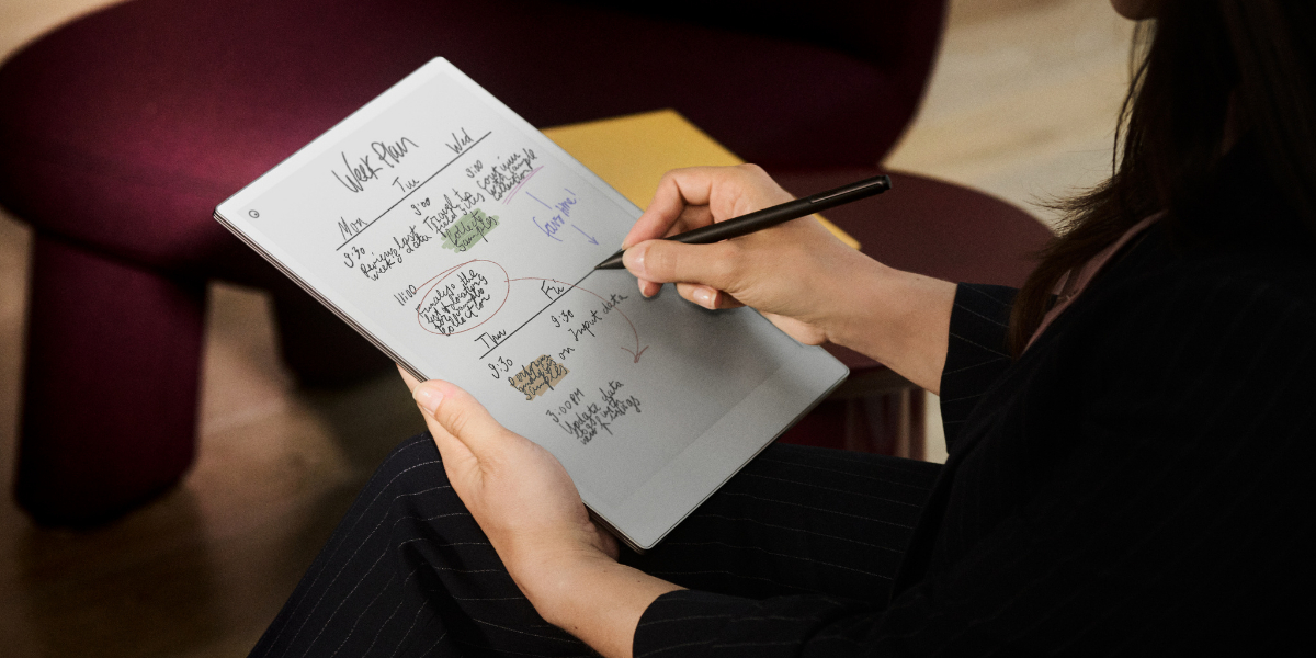 Person writing notes on an electronic tablet with a stylus, with colorful handwritten text and illustrations displayed on the screen.