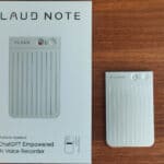 Plaud Note AI voice recorder alongside its packaging on a wooden surface.