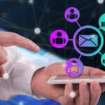 A person touches a smartphone displaying connected icons of people and an envelope, symbolizing communication or networking.