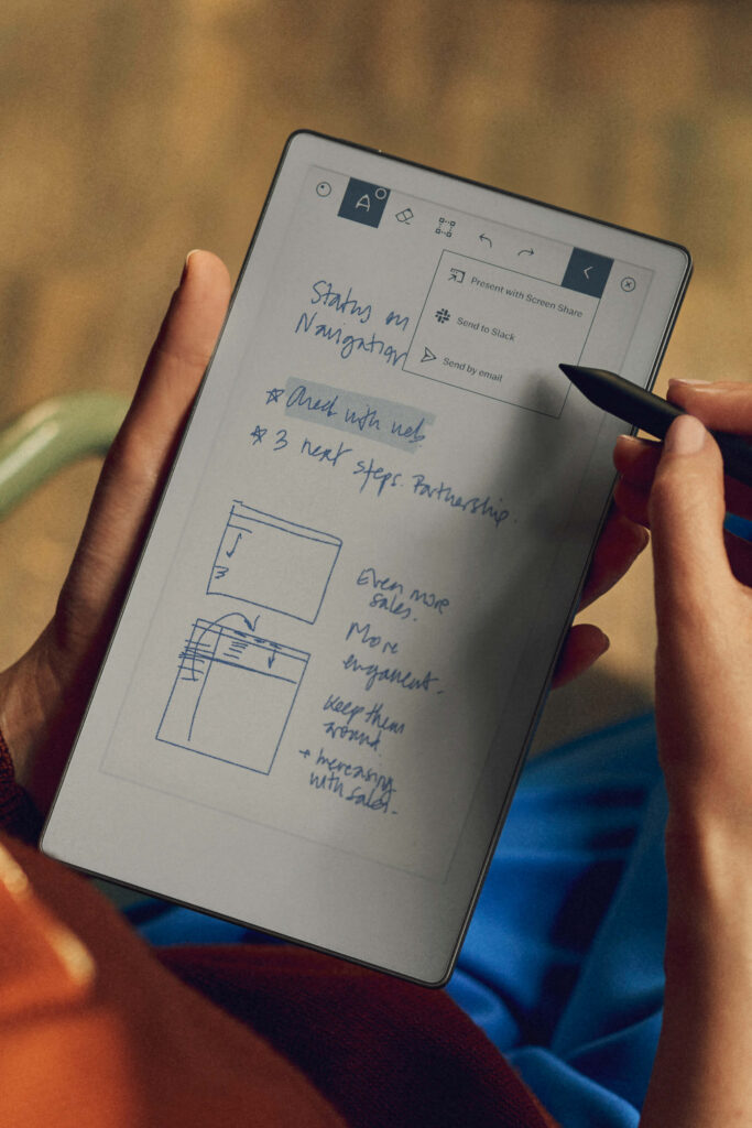 Person writing notes and drawing diagrams on a tablet with a stylus, displaying handwritten text and digital sharing options on the screen.