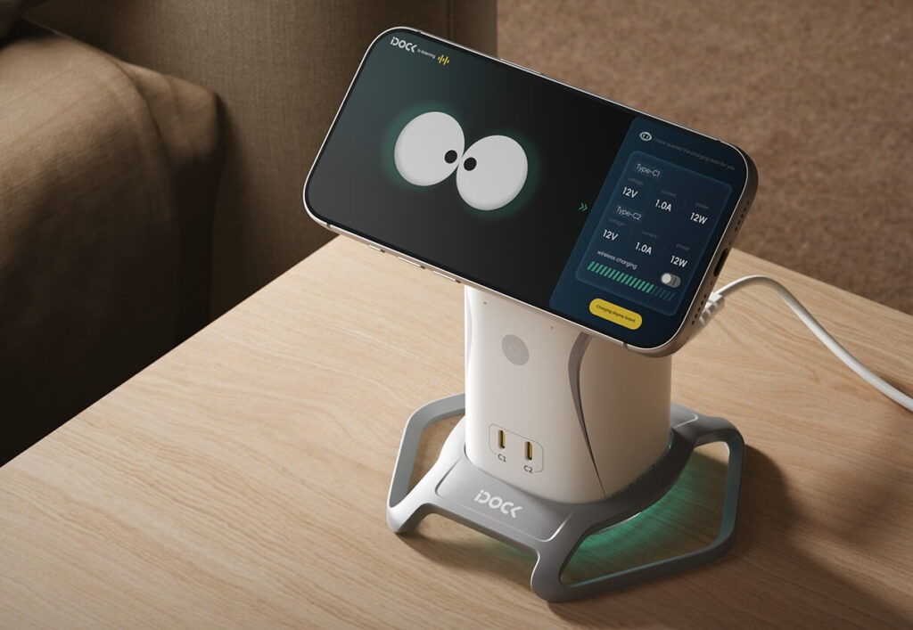 A smartphone displaying an app is docked on a smart charging station with two electrical outlets, placed on a wooden table near a sofa.